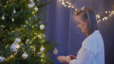 woman decorating christmas tree on christmas eve