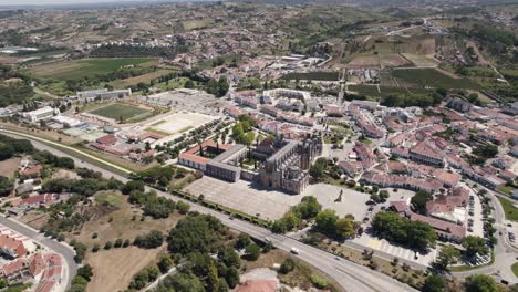 Aerial-backwards-view-of-the-monastery-of-Batalha,-with-its-surrounding-wide-area