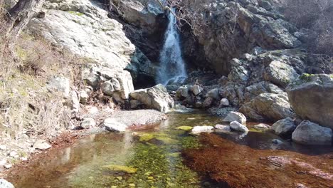 drone footage, flying close to the water surface of a river, towards a waterfall in the balkan mountains near the town of sopot, bulgaria