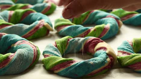 rociando harina sobre bagels de colores listos para ser horneados