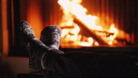 a man in warm socks warms his feet by the fireplace