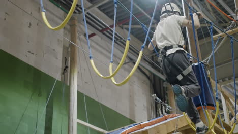 person navigating an indoor rope obstacle course