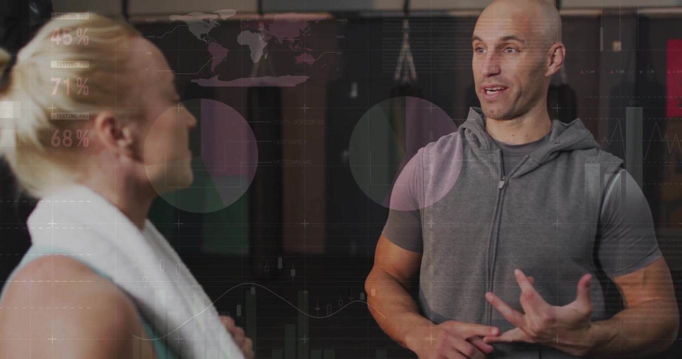 Mid adult woman approaching male trainer in gym, showing animated charts as trainer outlining tips