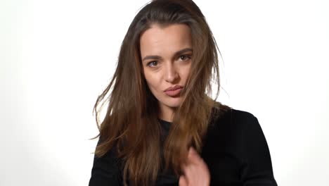 a mysterious woman with brown eyes in a black jumper straightens her magnificent hair on a white background in the studio.