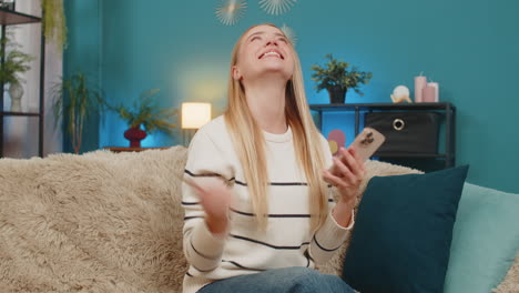 caucasian woman paying purchase on sofa with mobile phone credit card smiling successful indoors
