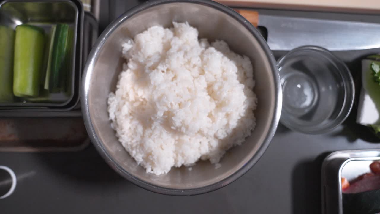 A bird’s eye view of rice and various sushi ingredients, showcasing the essential components used in traditional sushi preparation, arranged neatly for a top-down perspective.