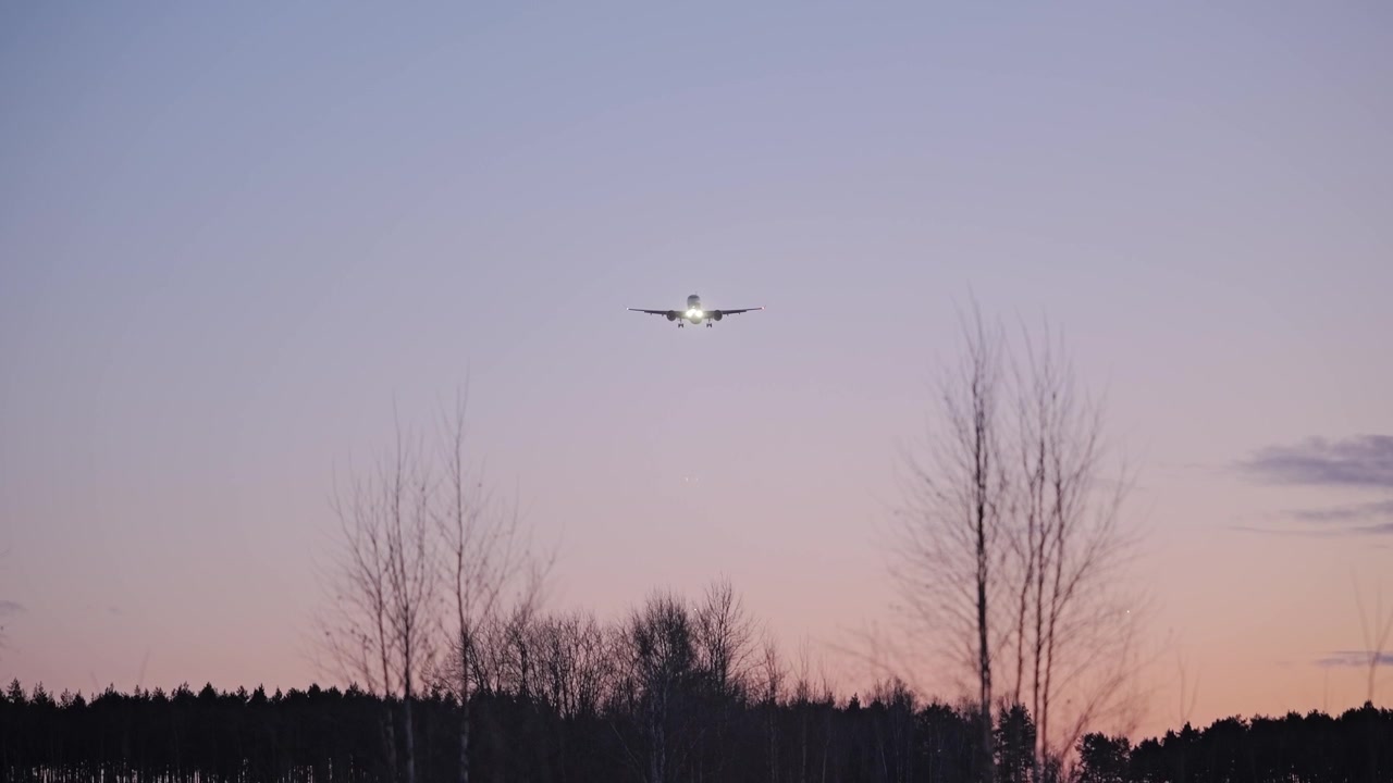 Flygspanare ser ett kommersiellt jetplan på väg ner mot Rigas flygplats i skymningen.