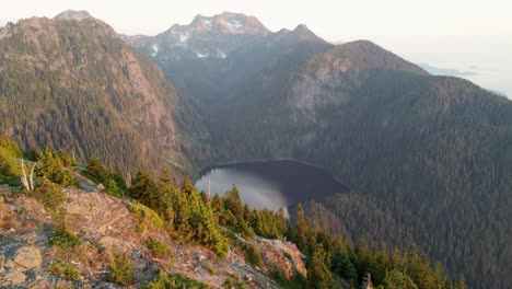 Lago-En-El-Paisaje-Montañoso-Al-Atardecer-Mientras-La-Cámara-Se-Desplaza-Hacia-Arriba---Imágenes-De-Drones