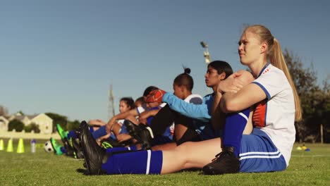 Weibliche-Fußballmannschaft-Streckt-Ihre-Beine-Vor-Dem-Training-Auf-Dem-Fußballplatz.-4k