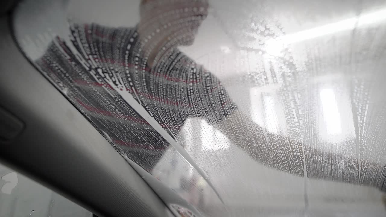 Worker washing car by foam sponge