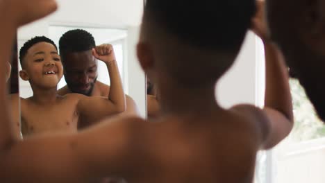 Afroamerikanischer-Vater-Und-Sohn-Spielen-Gemeinsam-Im-Spiegel-Ihre-Muskeln