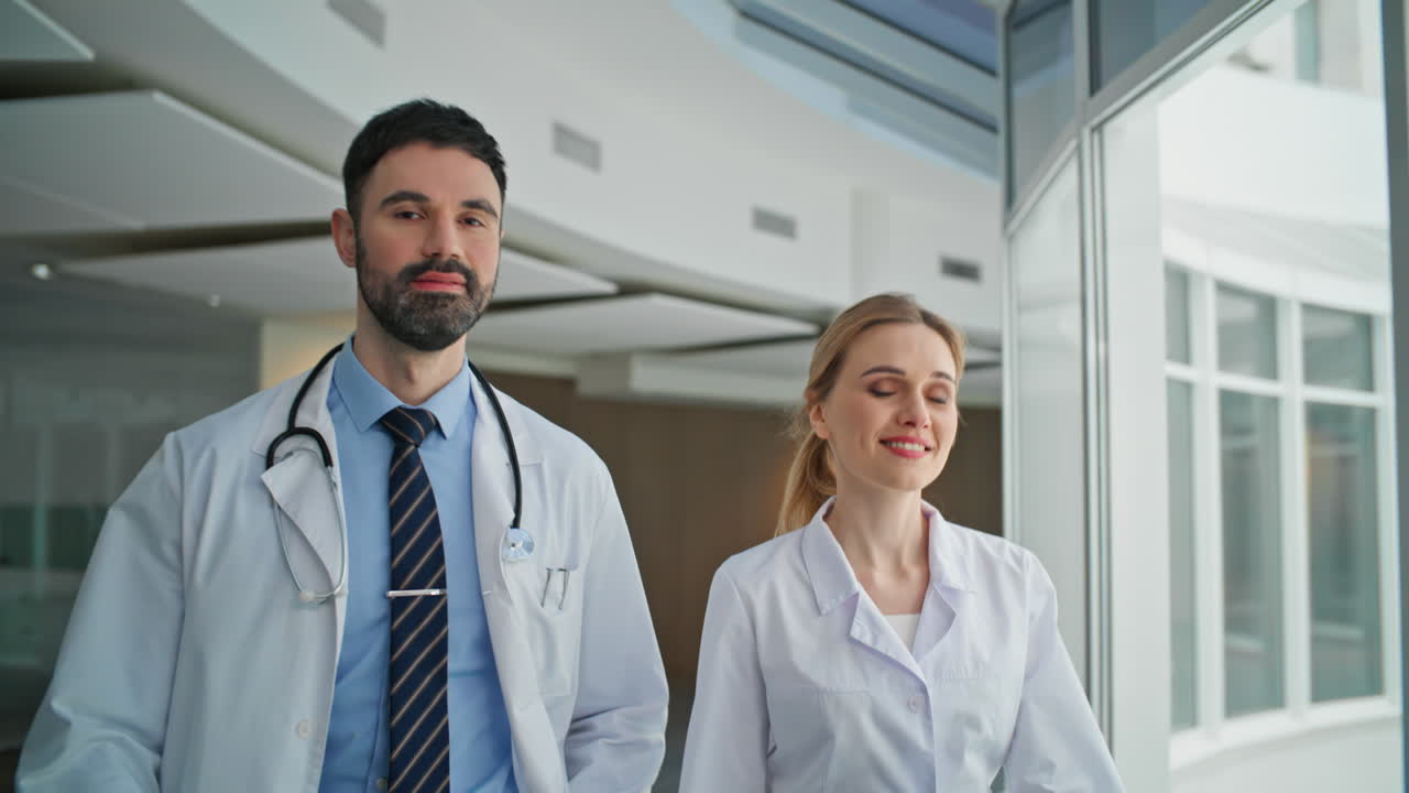 Medici sorridenti camminano insieme in una clinica moderna. Primo piano di professionisti sanitari
