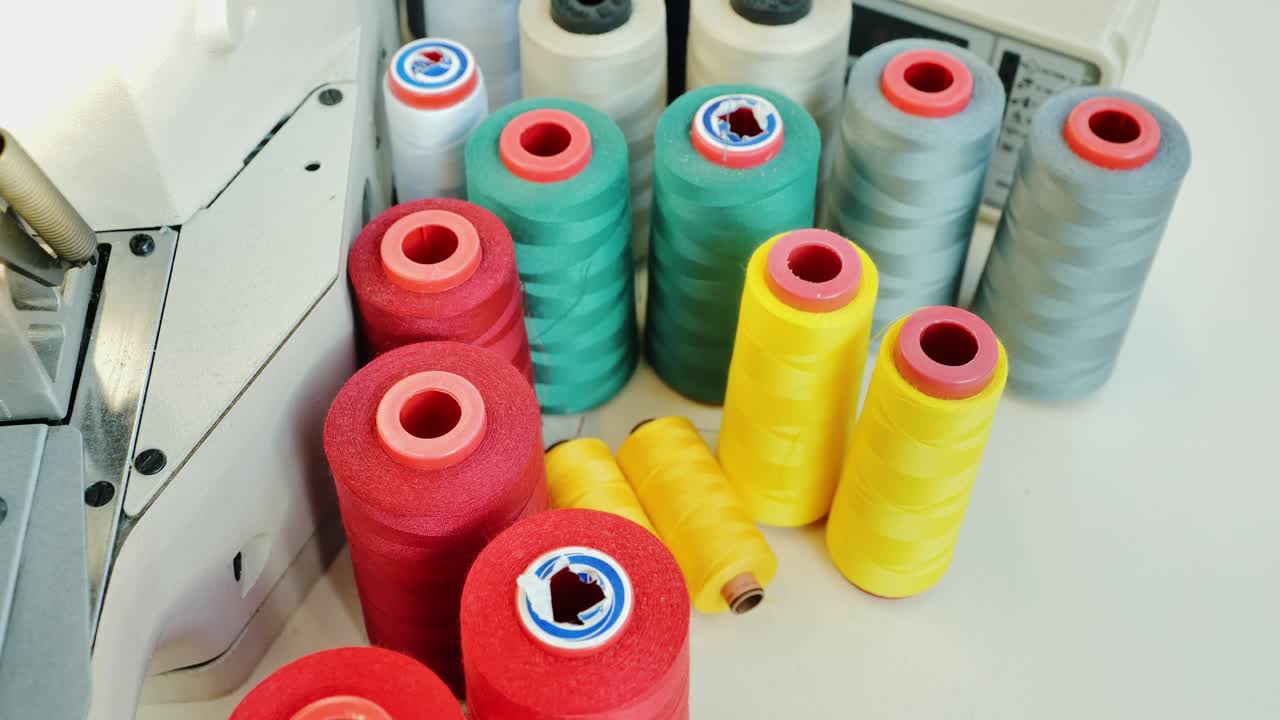 Slow upward camera move across colorful sewing threads in textile workshop