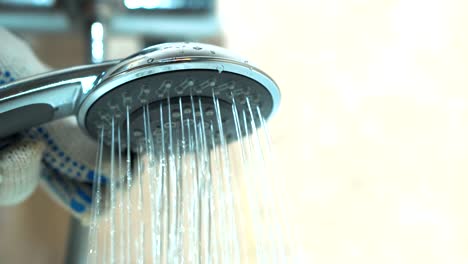 close - up of gloved hands plumber checks the work of the shower.