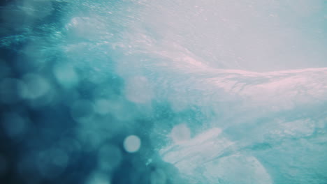 shoulder of wave rises as surfer carves dropping into barrel with sparkling water in tahiti