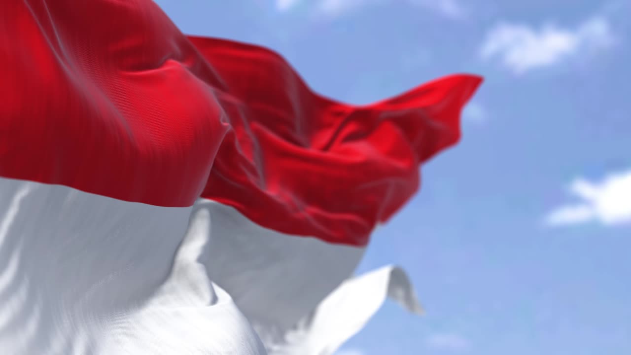 Detail of the national flag of Indonesia waving in the wind on a clear day.