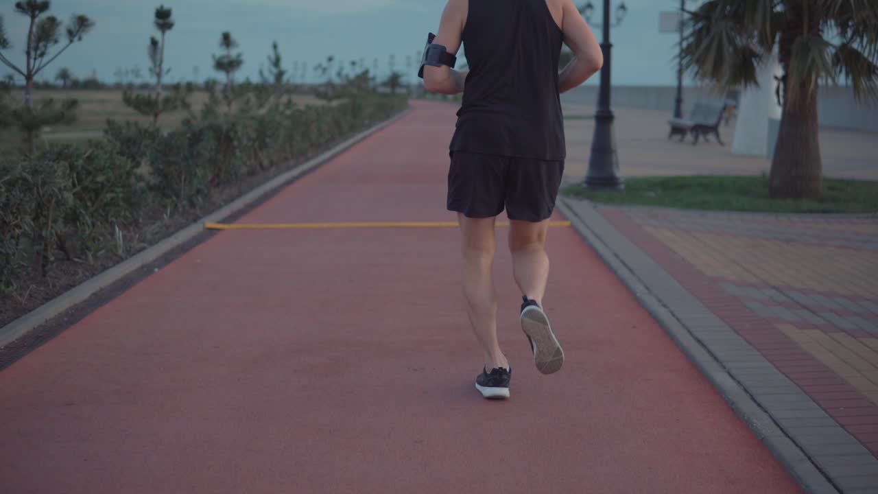 hombre corriendo por un camino costero al anochecer