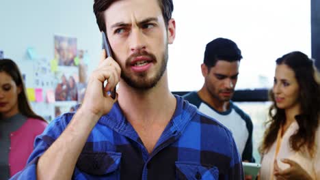 graphic designer talking on mobile phone while colleague discussing