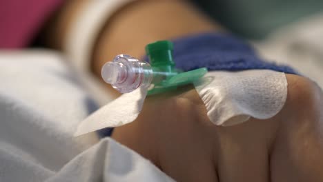 hand of patient with drip in bed of hospital