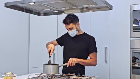 un joven está cocinando comida para entregar en su restaurante con una máscara protectora