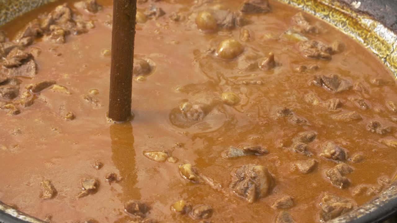 estofado de jabalí hirviendo en un caldero oscilante