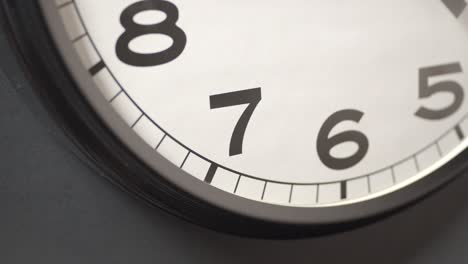 white clock face close up in time lapse on dark grey wall