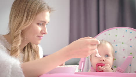 baby chewing toy and eating pureed food. teething baby eating breakfast.