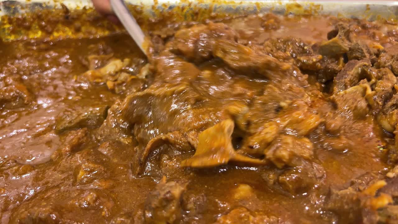 Closeup view of Bengali style mutton kosha and mixing with spatula.