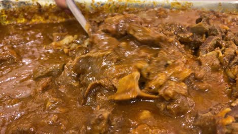 closeup view of bengali style mutton kosha and mixing with spatula.