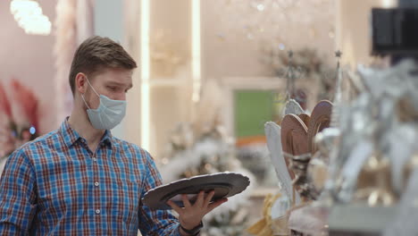 a man in a protective mask in a jewelry store and garlands with toys for christmas trees and at home. christmas garlands and decor