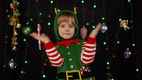 Kid-girl-in-Christmas-elf-Santa-helper-costume-dancing,-fooling-around.-New-Year-holiday-celebration