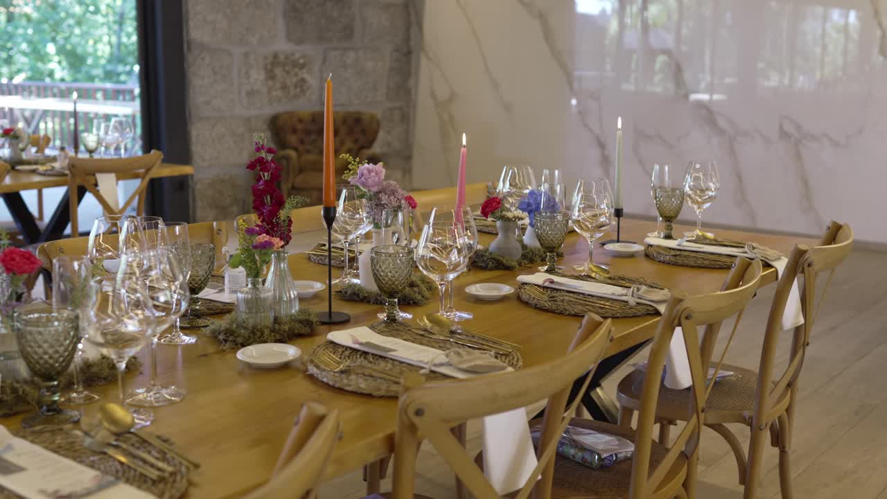 Long wooden wedding table with candles, floral decor, and elegant tableware