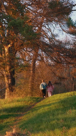 young friends running on nature background in autumn. happy couple having a scamper in the forest in the morning. vertical video