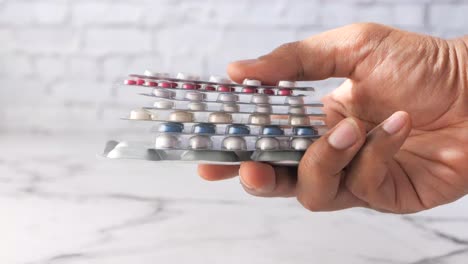 hand holding stacked blister packs of various pills