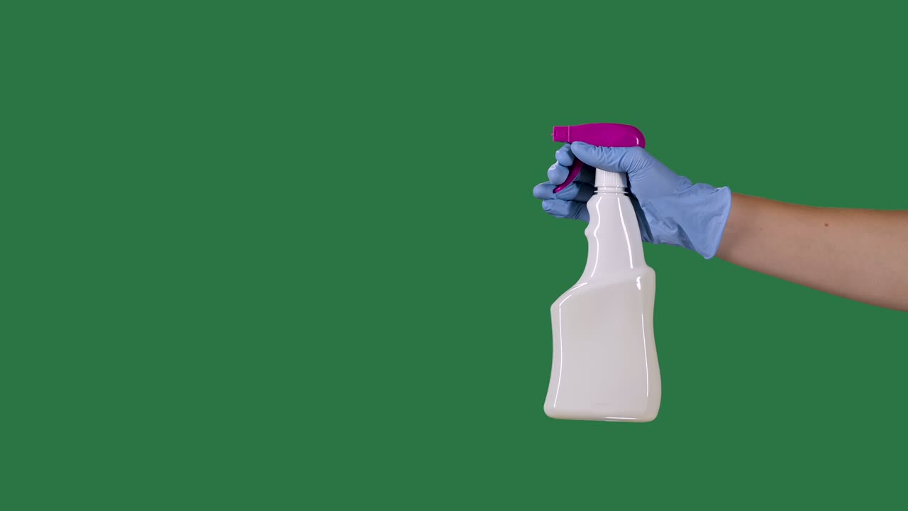 Man in protective gloves sprays a cleaning hygienic spray for disinfection and prevention of COVID 19. Green screen, chroma key. Slow motion. Close up
