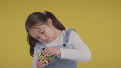 retrato de estudio de una joven en el espectro asd resolviendo un cubo de rompecabezas contra un fondo amarillo 1