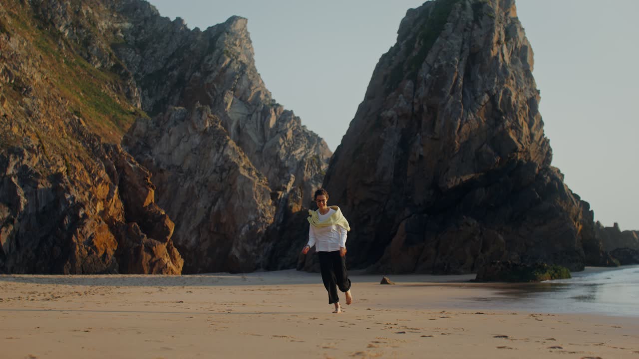 mujer corriendo en una hermosa playa con costa rocosa