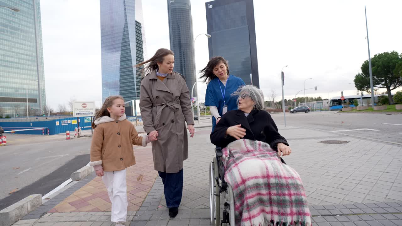 Badante che spinge un'anziana in sedia a rotelle con la famiglia in un contesto urbano