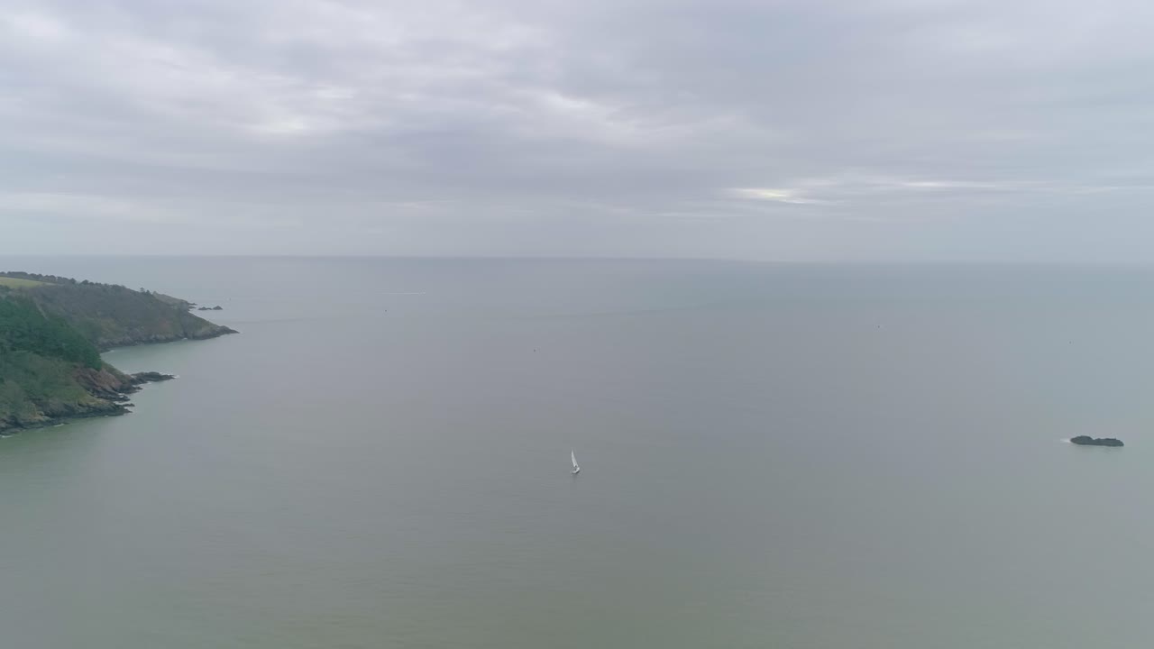 요트는 절벽 시골 녹색 해안선에 가까운 광활한 바다에서 항해합니다.