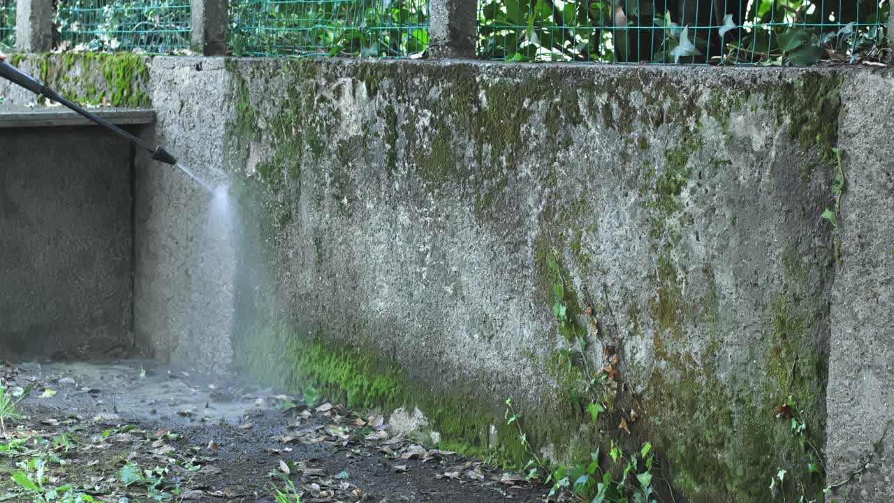 el hombre usa una lavadora a presión para eliminar la suciedad del camino de entrada de concreto