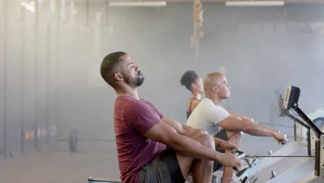 Diverse-group-fitness-class-training-hard-on-rowing-machines-at-gym,-in-slow-motion