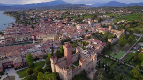 dolly cinematográfica aérea vista de lazise pueblo junto al lago italiano iluminado al atardecer