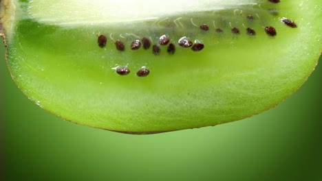 close up or macro of a slice of kiwi, a drop of water falls in slow motion. the fruit gives off freshness and is filled with juice rich in vitamins and energy. concept of fresh fruits, juices and kiwi