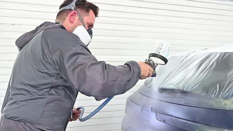 Spraying-varnish-on-trunk-of-dark-blue-vehicle,-close-up-view