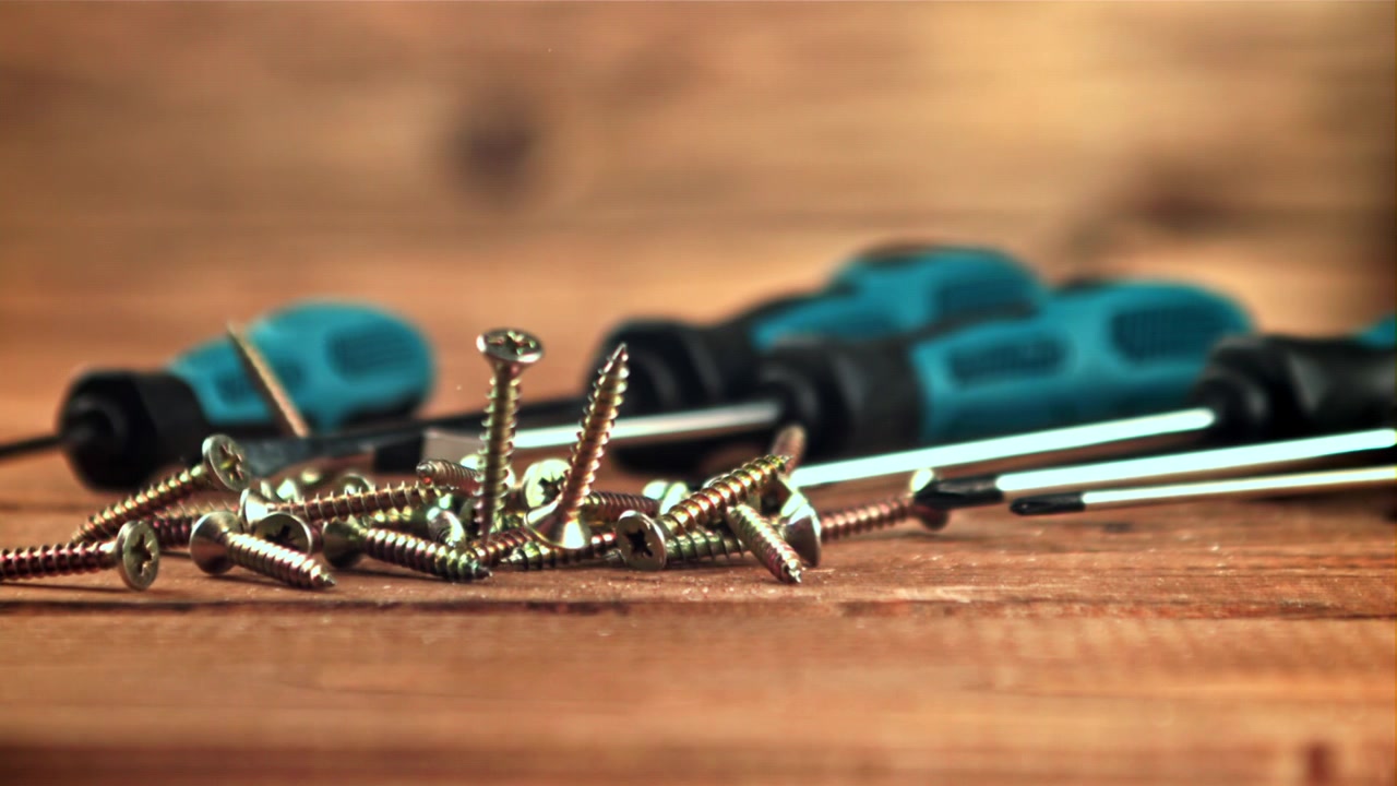 Screws Falling in Slow Motion onto a Wooden Surface with Screwdrivers