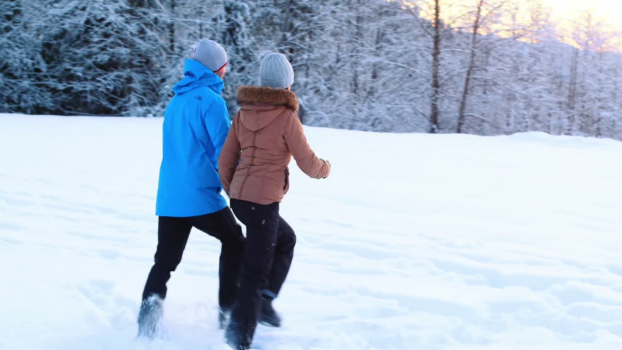 una pareja caminando en un bosque nevado.