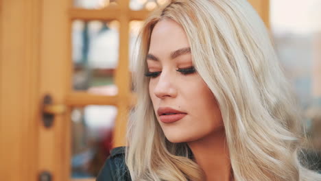 retrato de una mujer rubia bastante joven sonriendo maquillada con pintalabios mirando a la cámara
