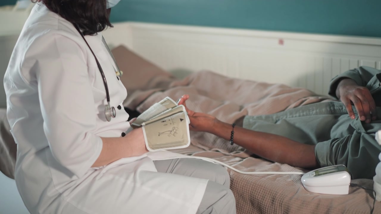 Medicinsk fagperson overvåger vitale tegn. Klinisk personale bruger digital enhed under patientvurdering. Plejepersonale udfører sundhedstjek med medicinsk udstyr i hjemmemiljø