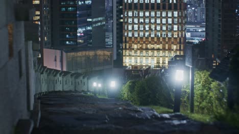 Night-city-town-hill-wall-with-lights,-buildings-and-wide-angle-cityscape-view-with-slow-zoom-in