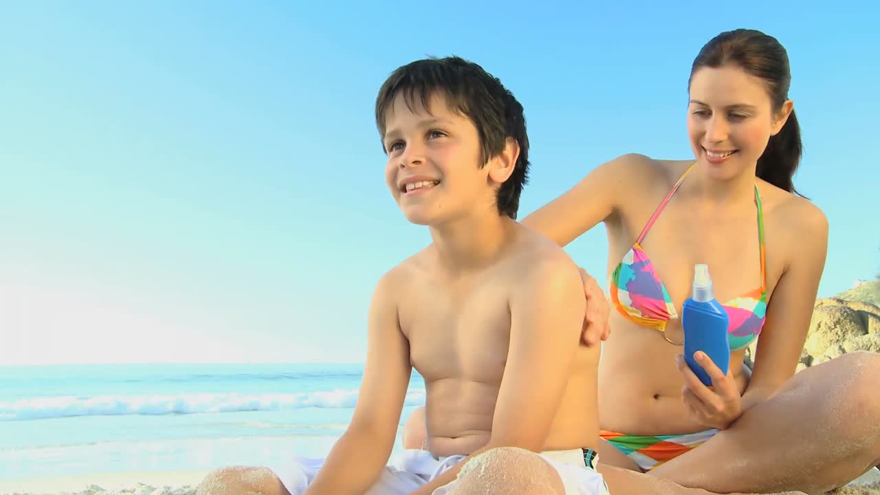 아름다운 어머니 가 아들 에게 자외선 차단제 를 쓰고 있다